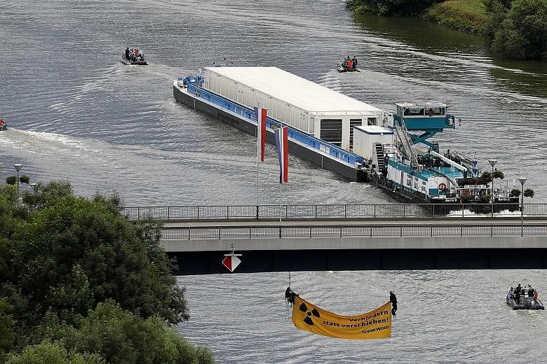 A ship with nuclear waste containers - or Castor containers - makes it way along the Neckar River in Bad Wimpfen, Germany, yesterday, as members of environmental organisation Robin Wood hang under a bridge to try and block it. It was the first of fiv