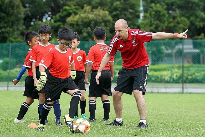 Ajax youth coach Casimir Westerveld with children from ActiveSG Football Academy. The writer says the lack of youngsters participating in competitive football beyond the youth level is an issue.