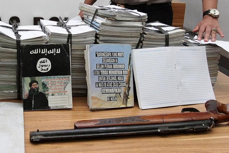 Notebooks inscribed with ISIS propaganda, seized during a raid on the home of a suspected militant, being shown at a press conference in Jakarta yesterday.