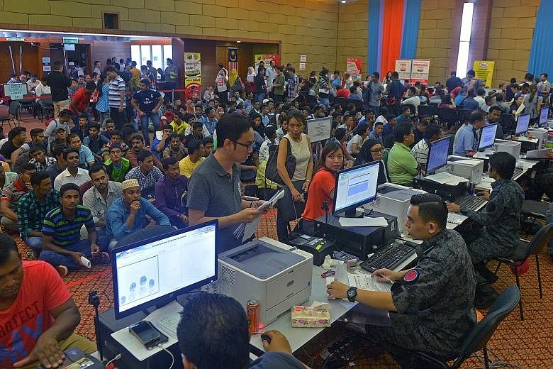 Employers and illegal workers applying for work permits at the Immigration Department headquarters in Putrajaya on Thursday night. The authorities are expected to begin rounding up illegal workers today.