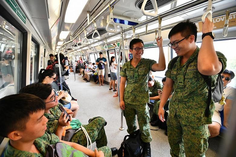 National servicemen enjoying a free train ride yesterday. SMRT was offering free train and bus rides to mark 50 years of NS.