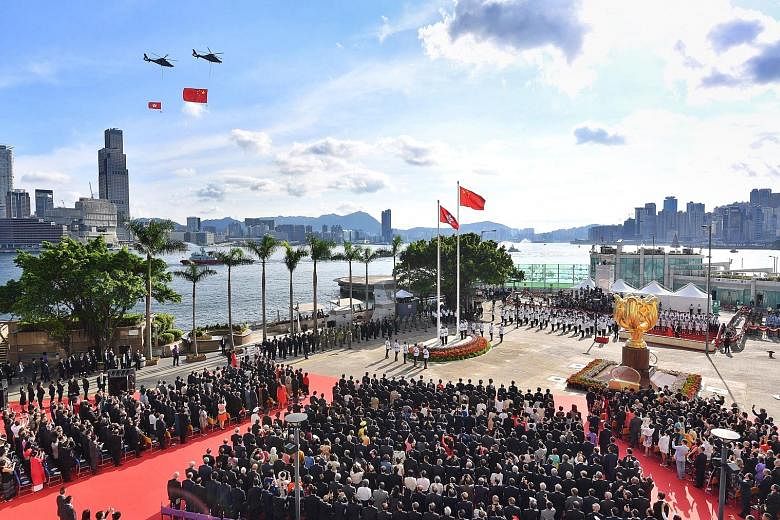 Helicopters carrying the Chinese (right) and Hong Kong flags flying past during a ceremony at Golden Bauhinia Square to celebrate the 20th anniversary of the city's handover to China yesterday. In her speech, new Chief Executive Carrie Lam pledged a 
