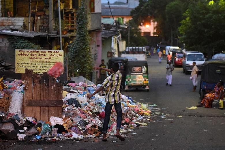 A man throwing trash in a Colombo street, where garbage has been piling up since Sri Lanka's main rubbish tip collapsed in April.