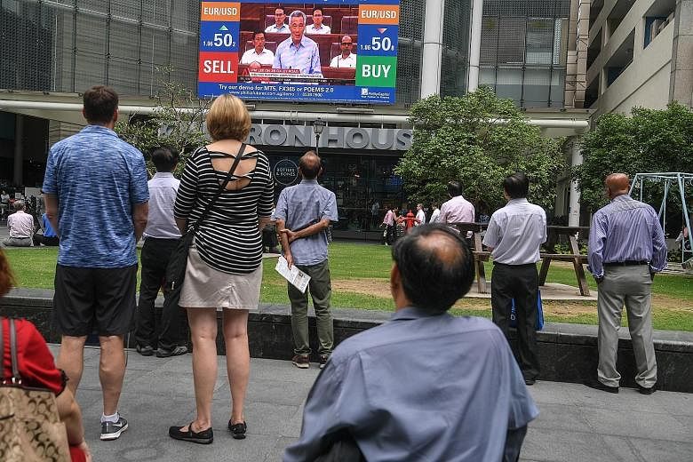People in Raffles Place watching a replay of Prime Minister Lee Hsien Loong's speech in Parliament addressing the 38, Oxley Road issues yesterday.