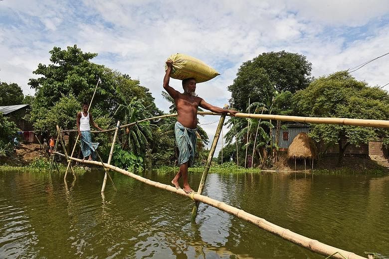 Villagers using a makeshift bamboo bridge to cross flooded areas in India's north-eastern state of Assam on Sunday. Weather officials say several rivers are maintaining a rising trend, and many of them have breached their banks.