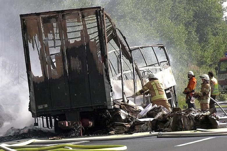 Firefighters at the scene after a tour bus rammed into a trailer truck and then burst into flames on a motorway near the Bavarian town of Stammbach in Germany yesterday.