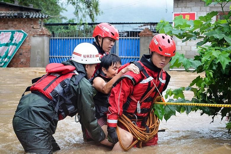 Rescue workers helping an elderly woman cross a flooded street in Guilin, Guangxi province. In Changsha (main picture), Hunan province's capital, days of torrential rain have caused the Xiangjiang river to exceed its record flood level.