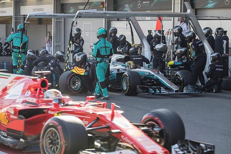 Mercedes driver Lewis Hamilton taking a pit stop during the Azerbaijan Grand Prix as Ferrari's Sebastian Vettel drives past.