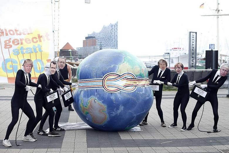 Activists wearing masks of some of the G-20 leaders demonstrating ahead of the summit's opening in the German city of Hamburg on Friday. The US is unlikely to set the direction this year, given its protectionist leader.