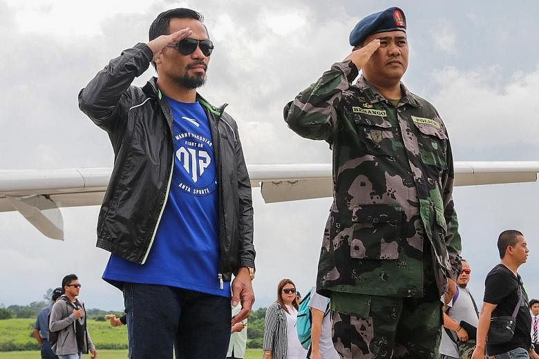 Manny Pacquiao (left) salutes as he arrives in the Philippines to a military guard of honour after losing his welterweight title to Jeff Horn in Brisbane.
