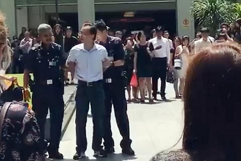 Police officers arresting Yan Jun at Raffles Place this week. He was fined for a similar offence last year.