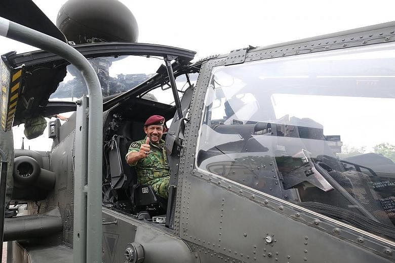 Sultan Hassanal Bolkiah in the cockpit of an Apache helicopter. He was taken on a tour of the army's Airborne-Trooper Training Facility and was later presented with the SAF's Honorary Advanced Military Freefall Wings to commemorate the event.
