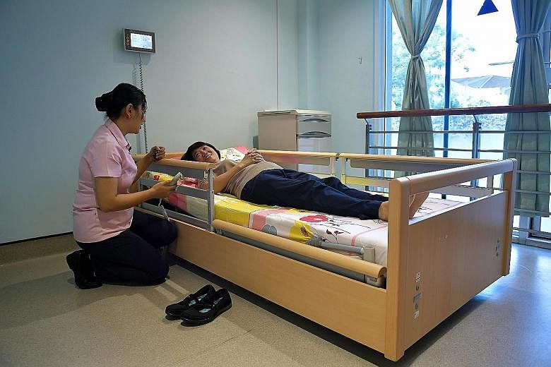 Senior staff nurse Khin Phone Tint, 33, showing how low the new nursing home's bed can go. The bed is designed to prevent a user from getting hurt if he or she falls out of it.