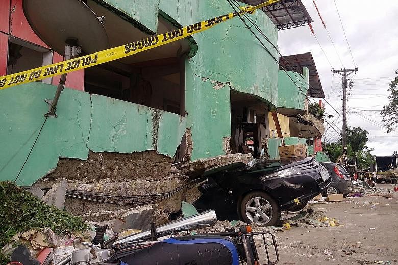 Vehicles buried under rubble after a 6.5-magnitude quake hit Kananga, on Leyte island, in central Philippines. Rescuers pulled out 13 people from a collapsed commercial building late on Thursday.