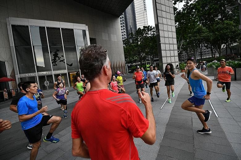 Left: Mok Ying Ren, who turned 29 on Thursday, is surprised with a belated birthday cake. Below: About 30 participants warm up with Singapore marathoner Mok (right, in blue) at Suntec City.