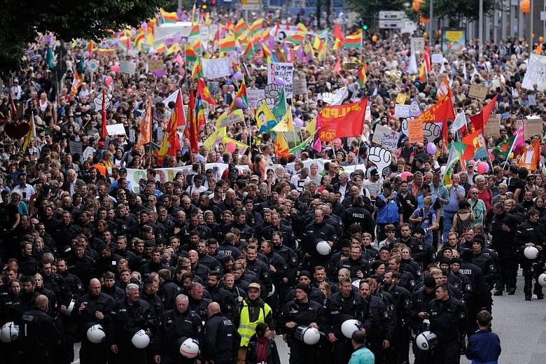 Thousands of protesters marched peacefully through Hamburg yesterday, the largest demonstration yet at an event that has been marred by looting, rioting and running street battles between black-clad anarchists and armoured police with water cannon ea