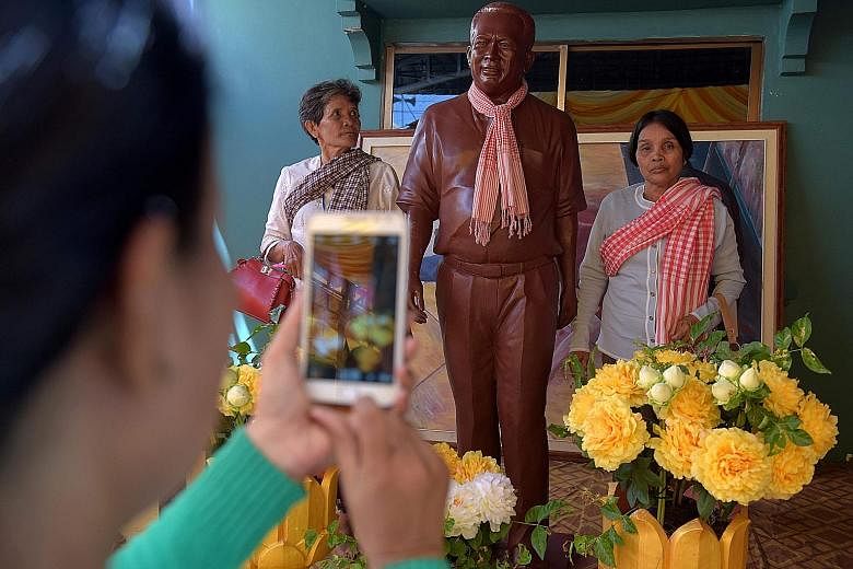 Visitors to the home of Mr Kem Ley's mother in Takeo province posing with a statue of the Cambodian critic on the first anniversary of his murder. The popular and charismatic political analyst was shot twice in the head on July 10 last year as he sip