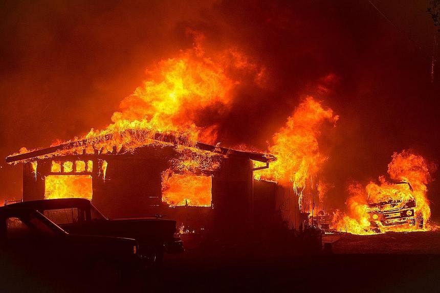 A car and house are engulfed in flames as a fire burns through a residential area in Oroville, California. Searing temperatures and parched land fuelled dozens of blazes in the West and South-west of the United States. There were 40 uncontained large
