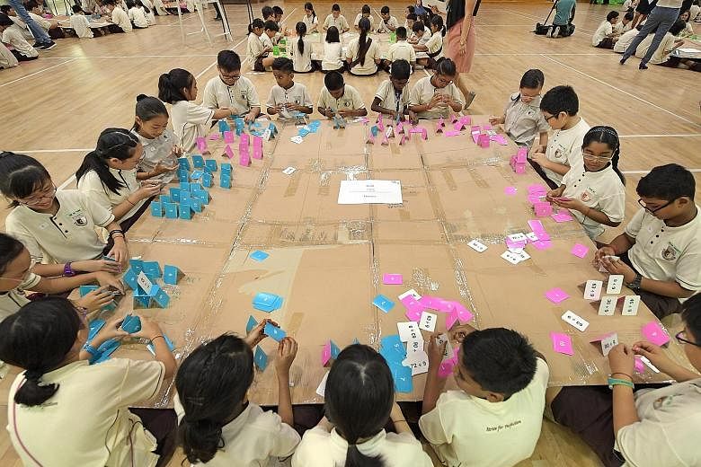 Primary 4 pupils of Boon Lay Garden Primary School building card houses on a large cardboard canvas resting on the laps of their peers. The set-up encouraged cooperation as any movement could cause the canvas to shake and make the houses fall. It was