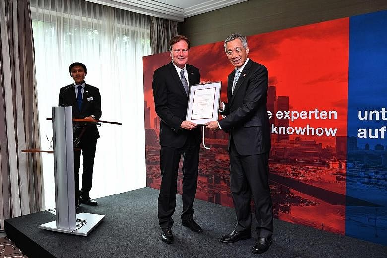 Above: One of the new economic ambassadors, Dr Roland Gerner, is senior adviser to technology group Heraeus. Left: Prime Minister Lee Hsien Loong presenting Dr Heinz-Juergen Bertram, chief executive of Symrise, with a certificate of appointment at a 