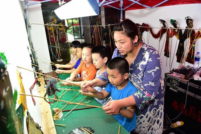 Chinese shadow puppet master Li Yuan showing children how to make their paper figures come alive in the ancient art of animation yesterday in Anhui province, eastern China. This is part of efforts by the Keqi community in Hefei city to introduce the 