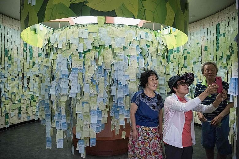 Visitors taking snapshots of messages calling for reunification at an observatory near the Demilitarised Zone (DMZ) separating the two Koreas on the island of Ganghwa, west of Seoul, on Tuesday. In the six months to June, 593 Northerners escaping pov