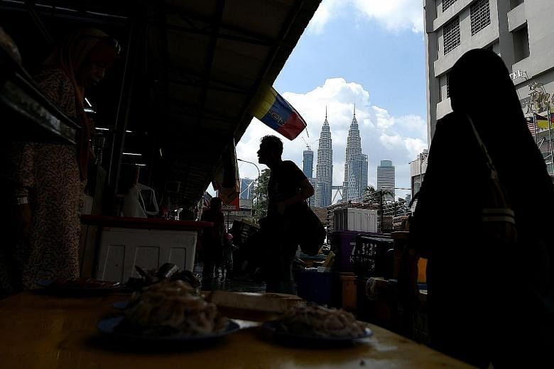 People shopping at a market in Kuala Lumpur. Malaysia's fortunes are turning with the World Bank raising the nation's growth forecast in June by the most in East Asia. Inflation is easing and foreign investors are more bullish on the stock market.