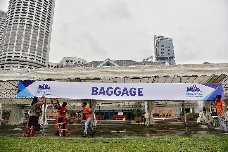 Workers carrying and setting up ST Run booths and signage in front of the Singapore Recreation Club at the Padang ahead of race day tomorrow morning.