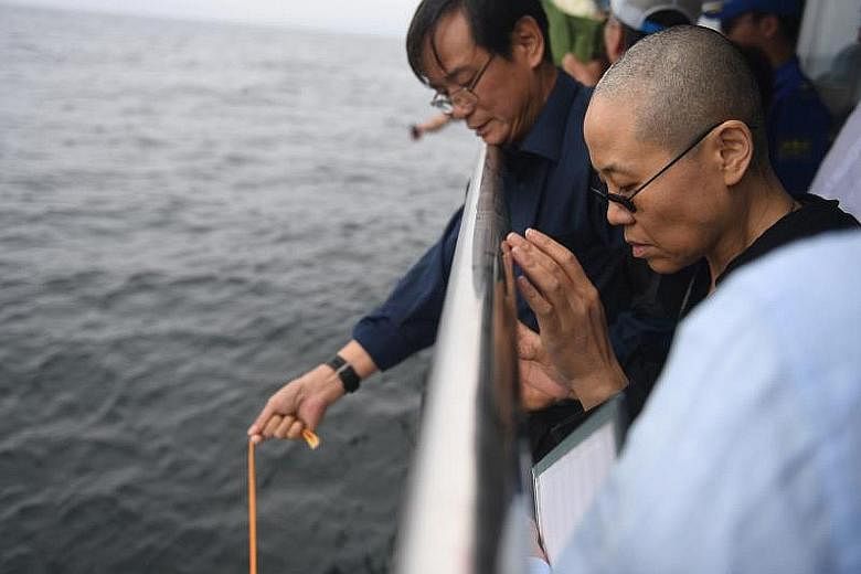 Poet Liu Xia, wife of the late Chinese Nobel Peace Prize laureate Liu Xiaobo, holding his portrait during his funeral in Shenyang, Liaoning province, yesterday. A municipal office official said the Nobel laureate's ashes (believed to be in box) were 