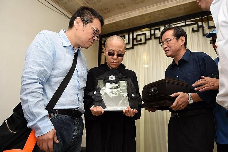 Poet Liu Xia, wife of the late Chinese Nobel Peace Prize laureate Liu Xiaobo, holding his portrait during his funeral in Shenyang, Liaoning province, yesterday. A municipal office official said the Nobel laureate's ashes (believed to be in box) were 