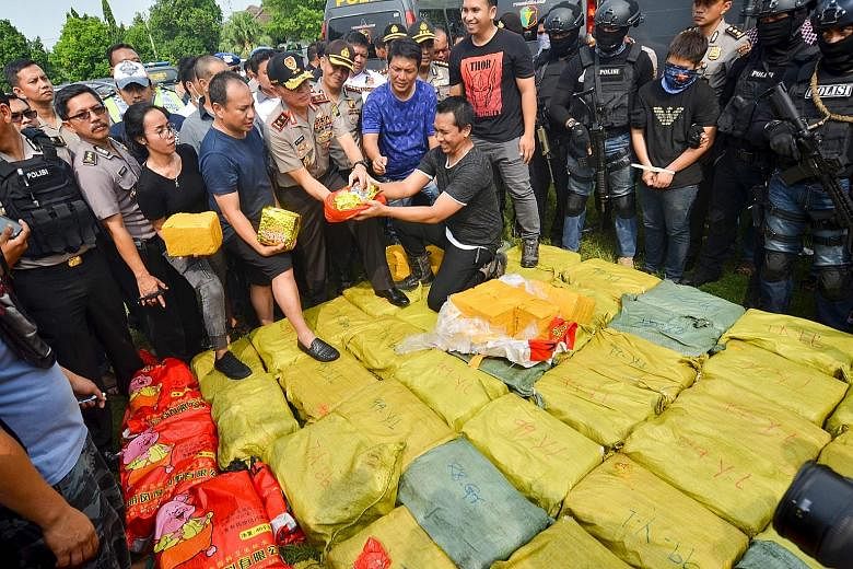 Indonesian police displaying one of the suspects (right, wearing mask with hands tied) and drugs seized during the raid in Anyer, Banten, on Thursday. The drugs were valued at almost 2 trillion rupiah (S$206 million).