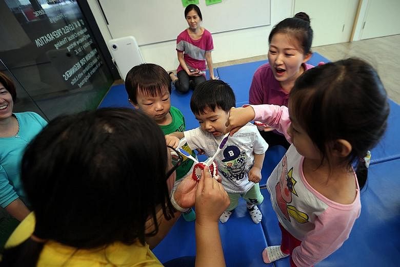 Head teacher Wang Mengxi (back to camera) and assistant teacher Diao Kejia teaching Chevonne Chia, three; Luke Teo (centre), two; and Ezra Siew, two, about oral hygiene at EduGrove Mandarin Enrichment Centre
