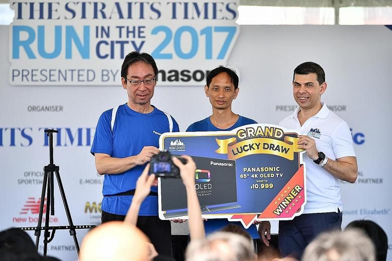 Mr Lim Beng Wei (centre) was participating in the ST Run for the first time but it turned out to be a memorable one. The 43-year-old's race bib number was picked in a lucky draw yesterday and the software engineer took home the grand prize - a Panaso
