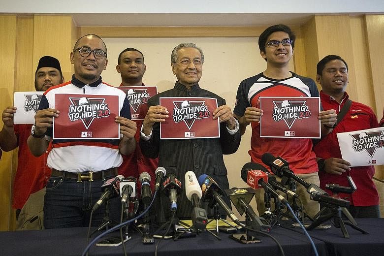 Dr Mahathir Mohamad (centre) holding up a poster for a debate he wants to hold with Prime Minister Najib Razak on alleged financial scandals under their respective premierships at a press conference yesterday.