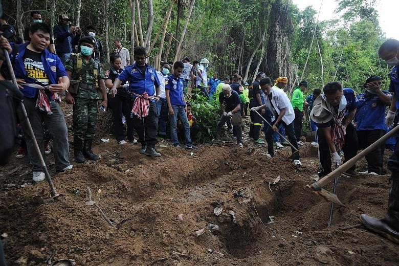 Rescue workers and forensic officials uncovering skeletons from mass graves of human trafficking victims at an abandoned jungle camp located by the Thai-Malaysian border in May 2015.