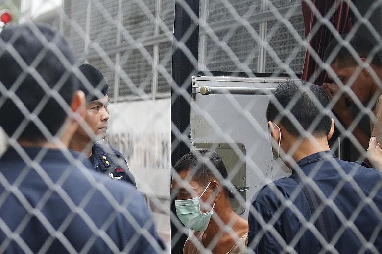 Senior military officer Manas Kongpan was declared guilty of transnational organised crime by the court. Thai police officers standing guard as suspects in a human trafficking case arrive at the criminal court in Bangkok yesterday. A landmark trial i