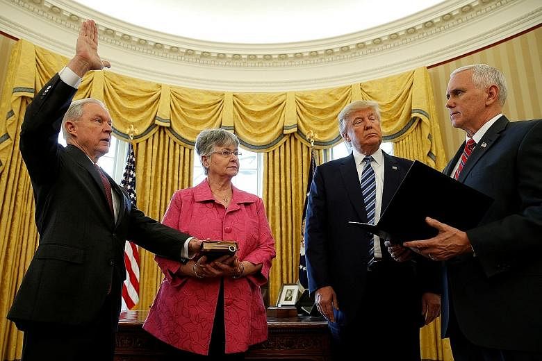 US President Donald Trump observing as Vice-President Mike Pence swears in Attorney-General Jeff Sessions while his wife Mary holds the Bible at the White House on Feb 9.