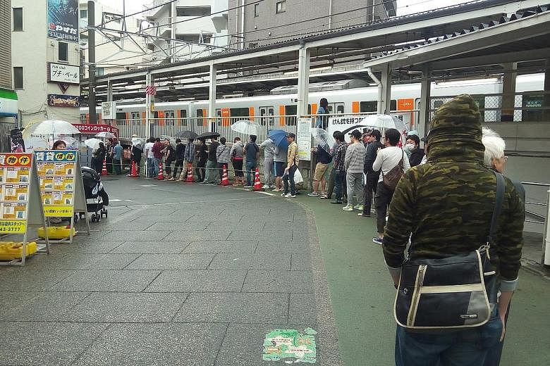 Top: A long queue forms outside a pachinko parlour near a train station in Tokyo before its doors even open one morning in May. Above: Pachinko machines are easy to play, readily available and cheap, drawing in an array of Japanese people from commut
