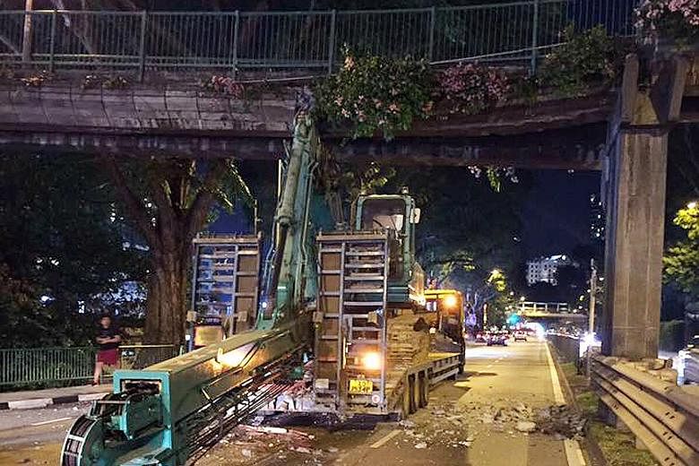 The arm of the excavator - which was being ferried by a trailer - lodged in the overhead pedestrian bridge in Balestier Road, part of which was closed after the accident last night.