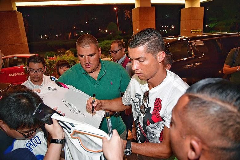 Ronaldo signing autographs for fans outside Great World City in the evening.