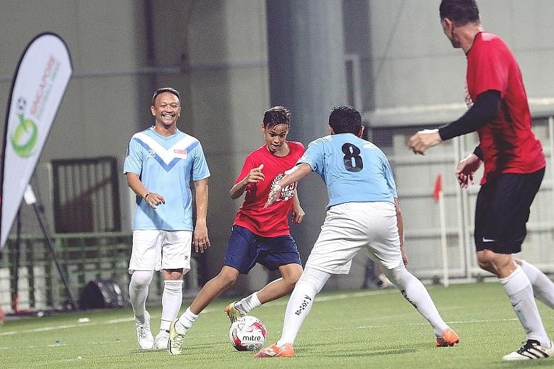 Former Singapore national football captain Fandi Ahmad watching his son Ilhan take on a defender during a friendly between ex-Singapore internationals and a team comprising celebrities and fans. The friendly, organised by the Football Association of 