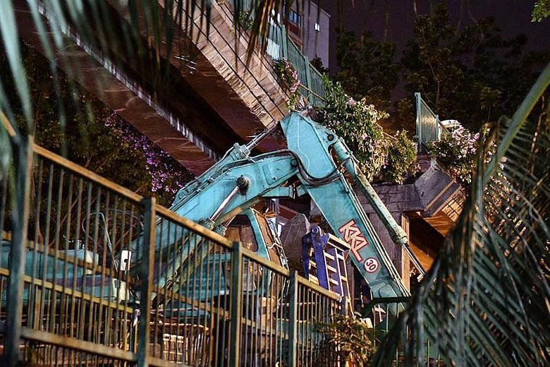 By 7.30am, the main section of the bridge was removed, leaving its middle pylon and staircase structures, allowing traffic to resume. The scene of the accident on Friday night, where the arm of an excavator being ferried on a trailer hit a pedestrian