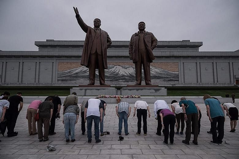 Tourists bowing before statues of late North Korean leader Kim Il Sung and his son Kim Jong Il at Mansu Hill yesterday. The US plans to bar Americans from travelling to the country, following mounting tensions over its missile and nuclear programmes,
