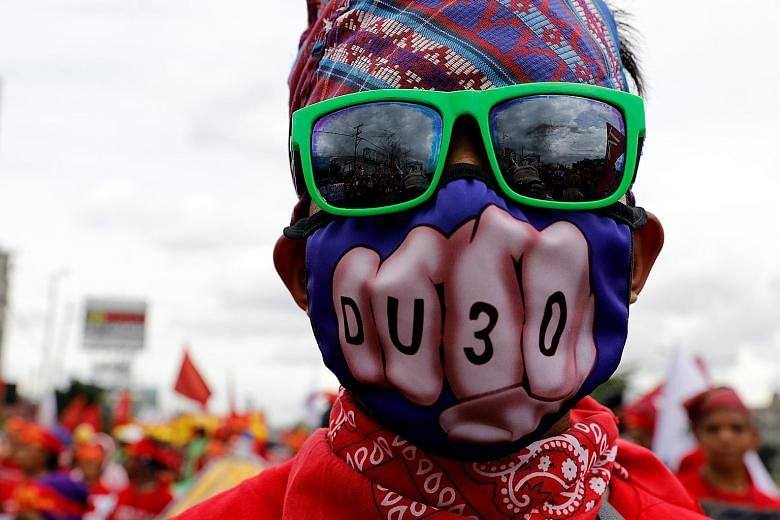 An anti-government protester, wearing a mask that plays on Mr Rodrigo Duterte's name, taking part in a march towards the Philippine Congress ahead of the President's second State of the Nation address yesterday.