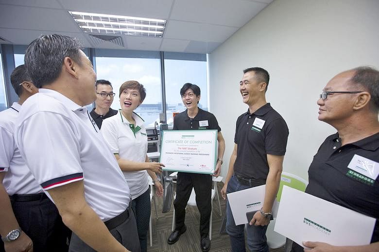 Mrs Josephine Teo and some of the bus captains chatting with Mr Melvin Yong (at left) at the graduation ceremony yesterday. SBS Transit trainee bus captain Aw Wei Han (centre) is the academy's 1,000th bus captain to pass the enhanced vocational train