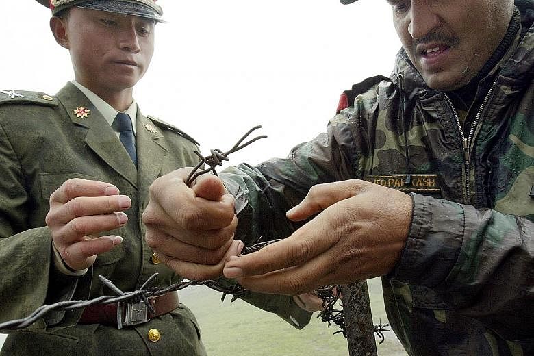 A Chinese soldier and an Indian soldier fixing a barbed-wire fence at the Nathu La border crossing between India and China in India's north-eastern Sikkim state in 2006. China and India have disputes in several areas along a 4,000km border, including