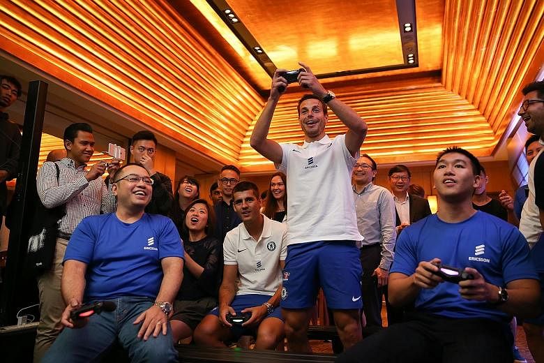 Chelsea striker Alvaro Morata and defender Cesar Azpilicueta (standing) playing Fifa at an event hosted by Ericsson yesterday. Morata will be the Blues' No. 1 choice up front this season.