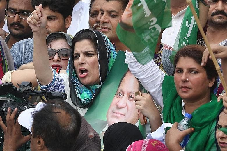 Supporters of Mr Nawaz Sharif, with one holding his picture, protesting in Lahore against the court verdict disqualifying him from holding the office of Prime Minister. Mr Sharif resigned soon after.