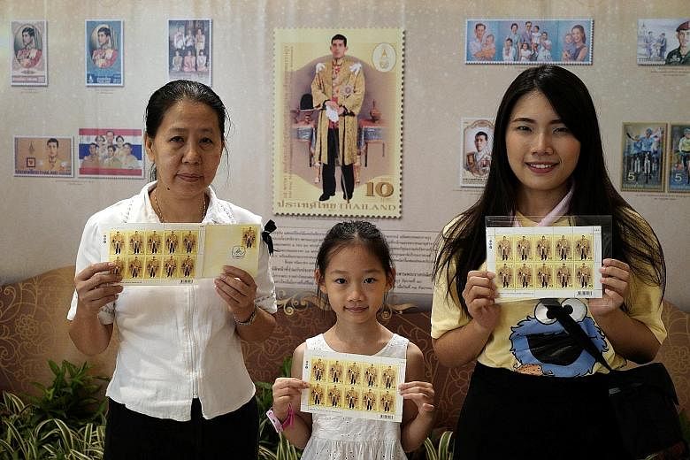 A Thai family with the special edition postage stamps of King Maha Vajiralongkorn released to mark his 65th birthday yesterday. Thai embassies around the world hosted mass alms-offerings to mark the day.