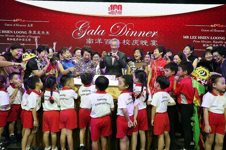 Prime Minister Lee Hsien Loong taking a shot of pupils with the anniversary cake. With him are (from fourth from left) Ms Chua Eng Eng, president of Nanyang Schools Alumni Association; Madam Wee Bee Hoon, honorary patron of Nanyang Family of Schools'